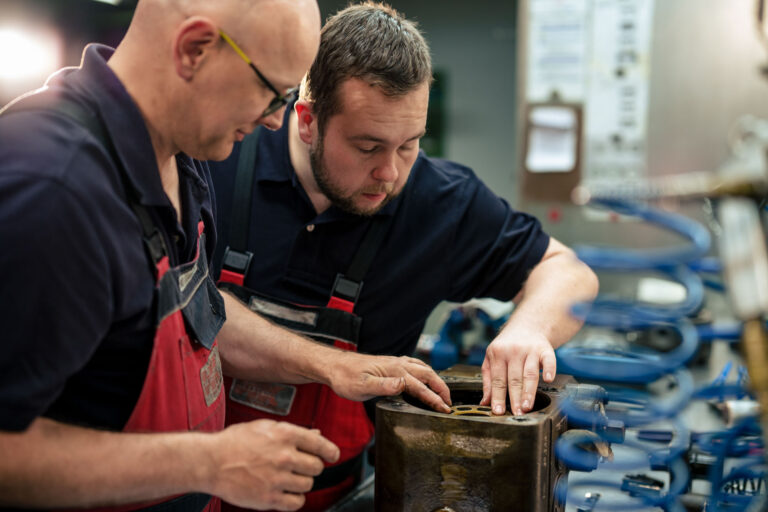 Zwei HK Hydraulikmitarbeiter schauen gemeinsam auf eine Hydraulikkomponente