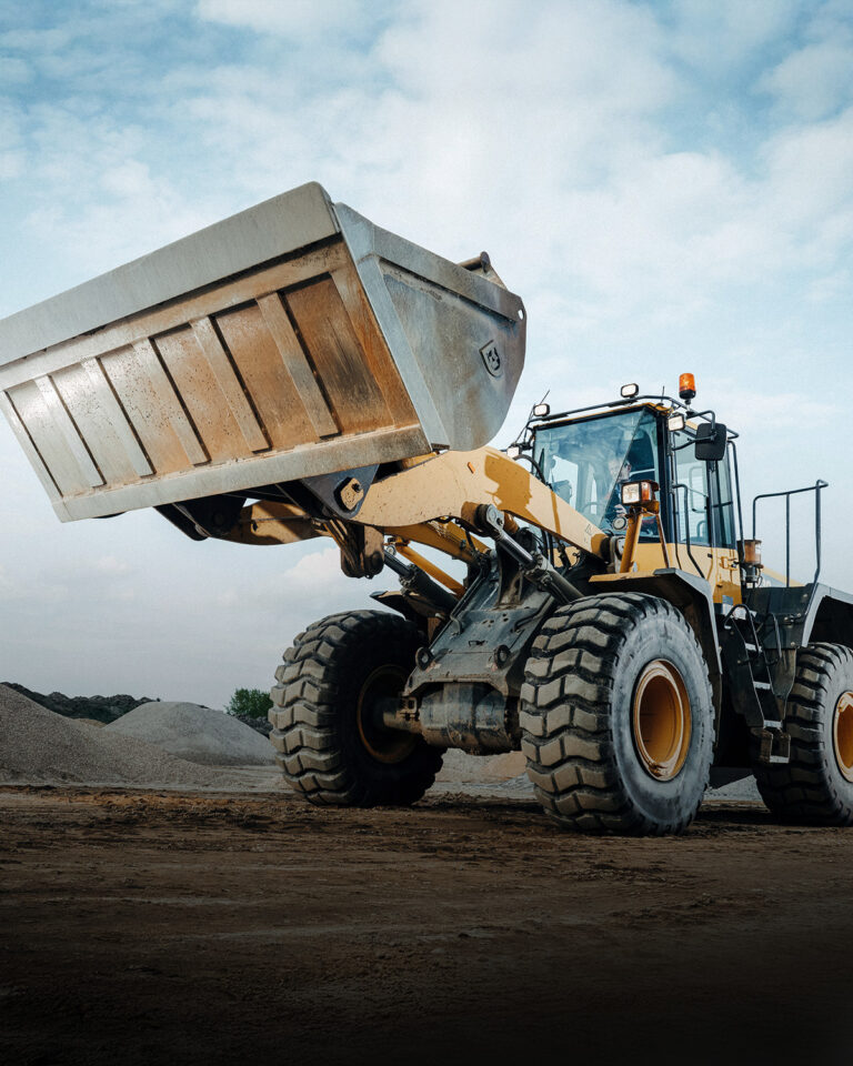 Schaufelbagger mit beladener Schaufel auf einer Baustelle
